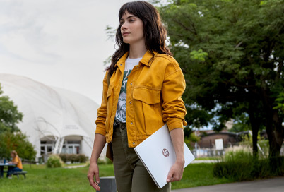 girl walking with an HP laptop in her hand and waring a yellow jacket