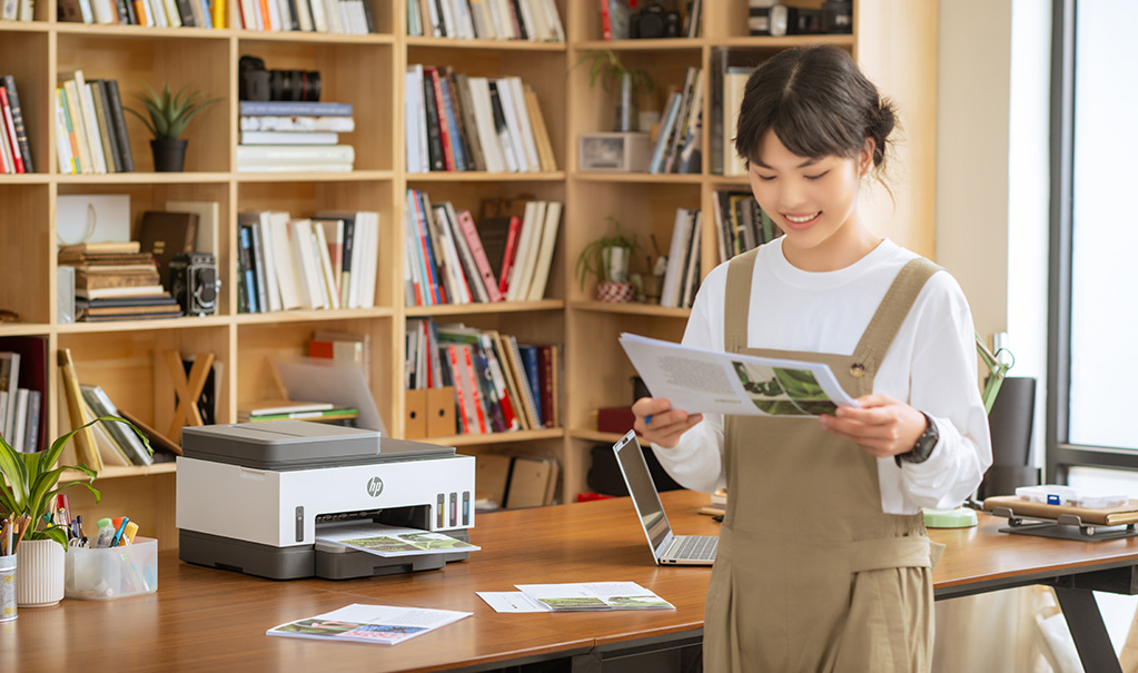 girl looks happy looking at the printout from a HP smart tank printer