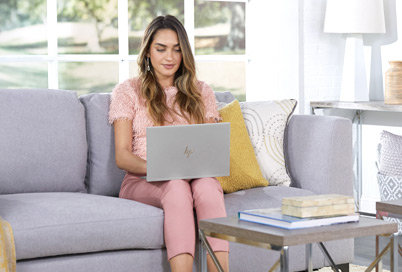Girl sitting on a couch working with an HP Envy