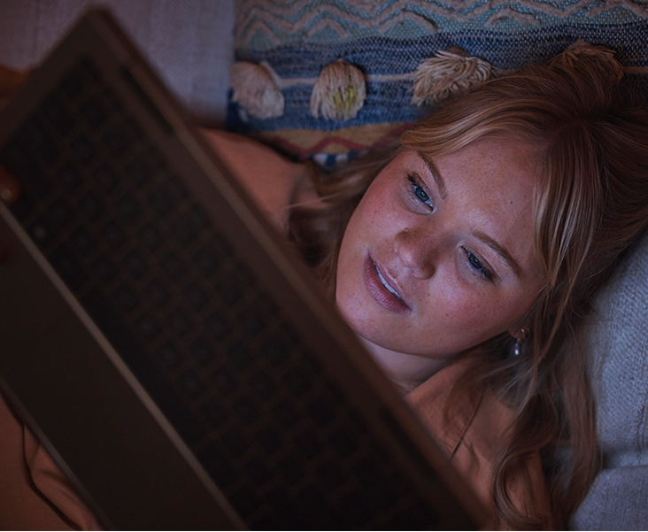 A girl watching laptop while sleeping on the bed