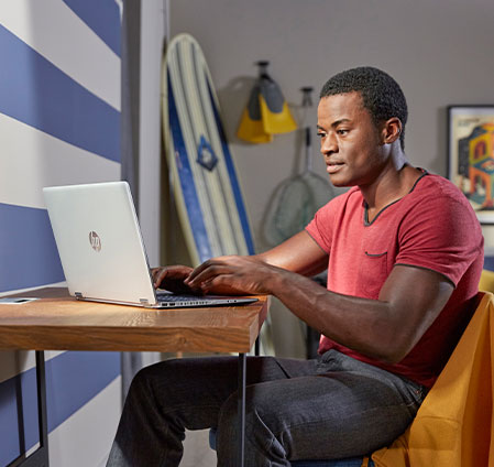 A man sitting at a table, focused on his laptop