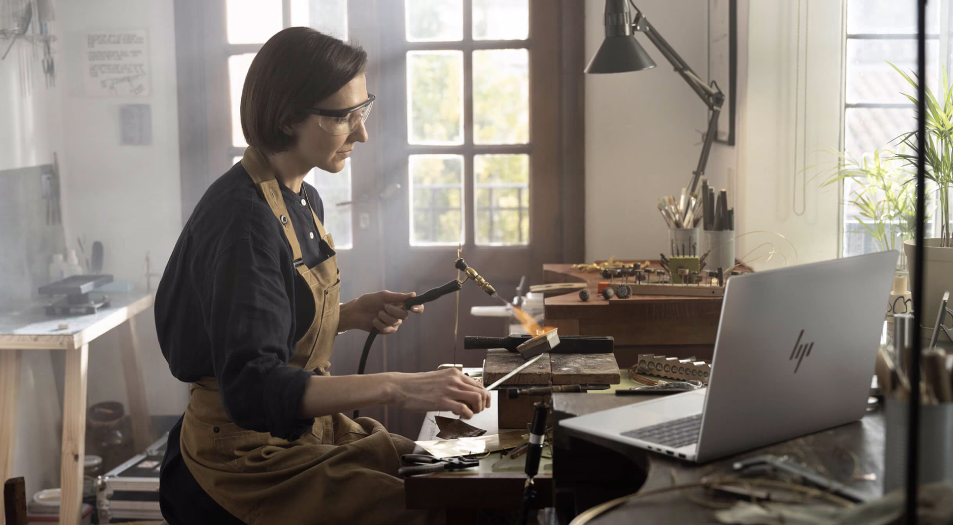 A woman focused on her HP laptop while seated at a desk in a well-lit room.